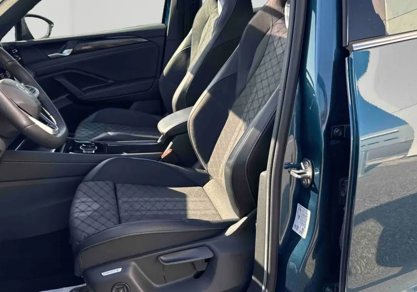 Vue intérieure côté gauche du Volkswagen Tiguan 2025 bleu, mettant en valeur les sièges avant sport en tissu et cuir.