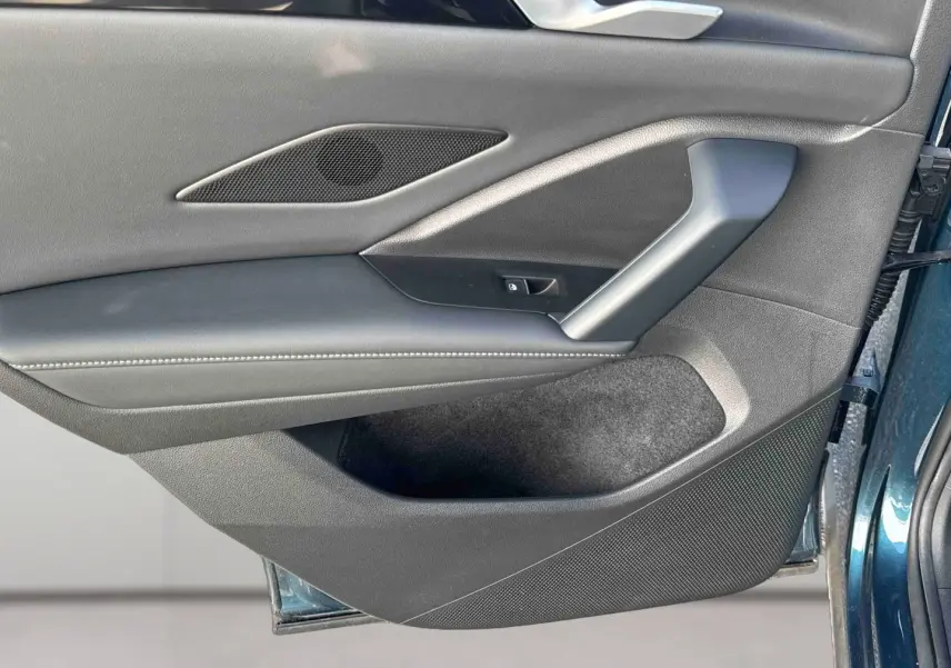 Vue rapprochée de la porte avant gauche du Volkswagen Tiguan 2025 bleu, montrant la garniture intérieure noire et les commandes.