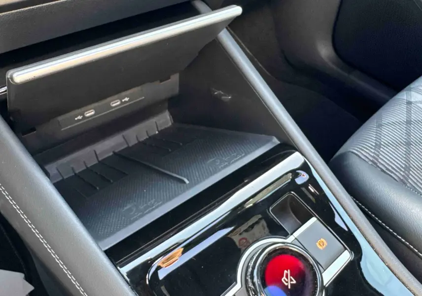 Gros plan sur la console centrale intérieure du Volkswagen Tiguan 2025, avec chargeur sans fil et frein de stationnement électronique.
