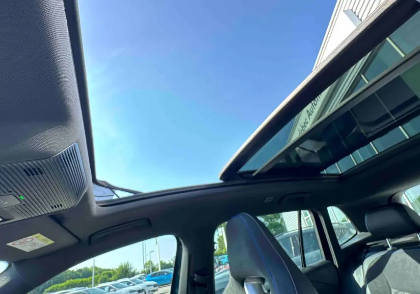 Vue intérieure du toit ouvrant panoramique et des sièges avant en cuir noir du Volkswagen Tiguan bleu 2025.