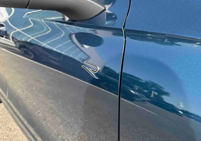 Vue rapprochée du côté gauche bleu métallisé du Volkswagen Tiguan 2025 avec logo R distinctif sur la porte.