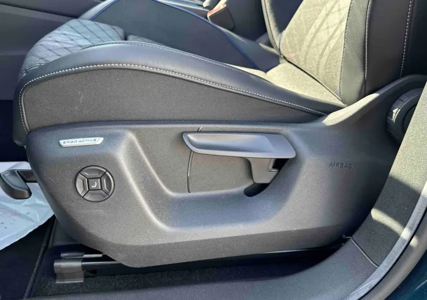 Détail du siège conducteur ErgoActive avec réglages manuels sur le côté gauche d’un Volkswagen Tiguan bleu.