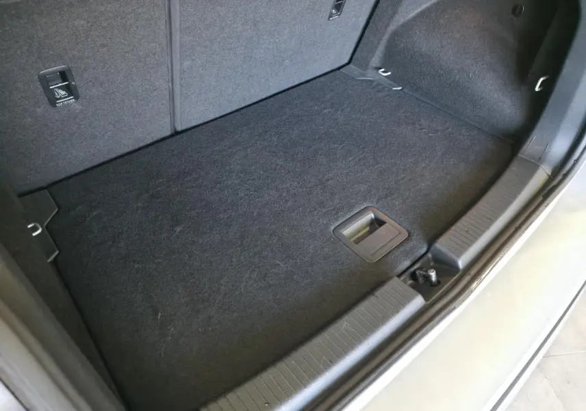 Coffre arrière ouvert du Volkswagen T-Cross gris, vue plongeante sur le plancher et les finitions intérieures.