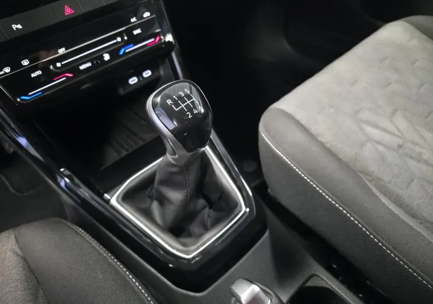 Gros plan sur le levier de vitesses manuel noir et la sellerie grise du Volkswagen T-Cross 1.0 TSI Life 2025.