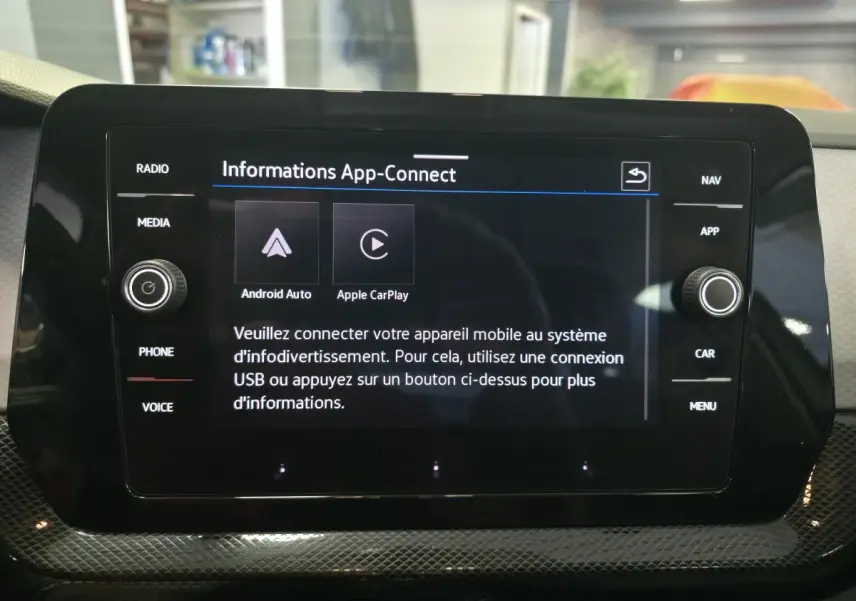 Écran tactile central noir affichant l'interface App-Connect dans l'habitacle d'un Volkswagen T-Cross gris.