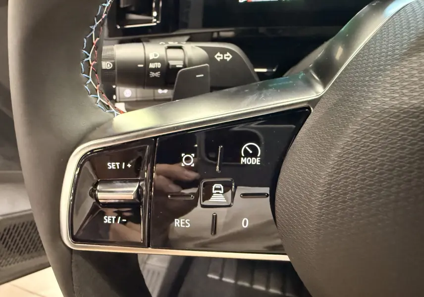 Gros plan sur les commandes au volant côté gauche du Renault Austral blanc nacré, avec surpiqûres tricolores visibles.
