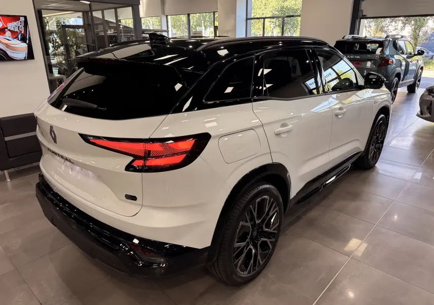 Vue 3/4 arrière droite du Renault Austral blanc nacré avec toit noir et jantes noires en concession.