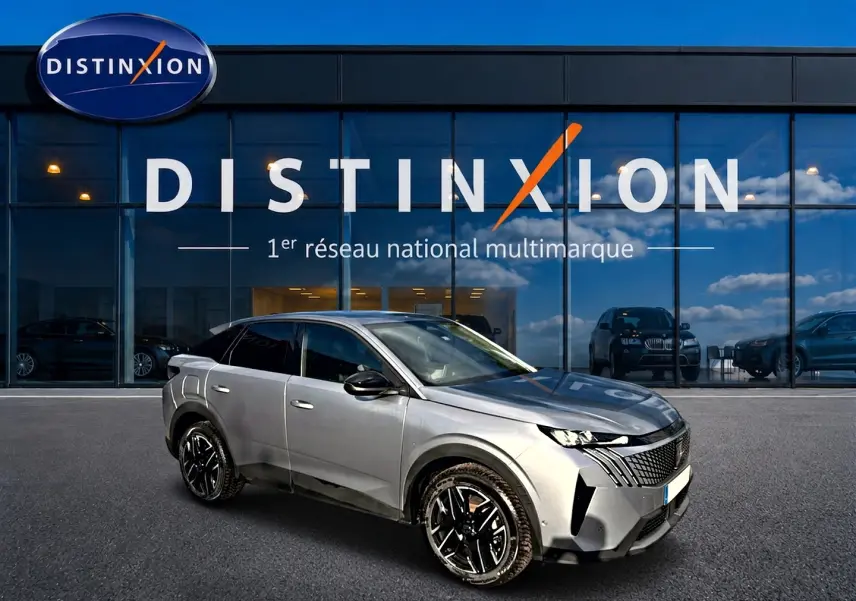 Peugeot 3008 gris artense en 3/4 avant droit, avec jantes alu noires et calandre distinctive, devant un showroom Distinxion.