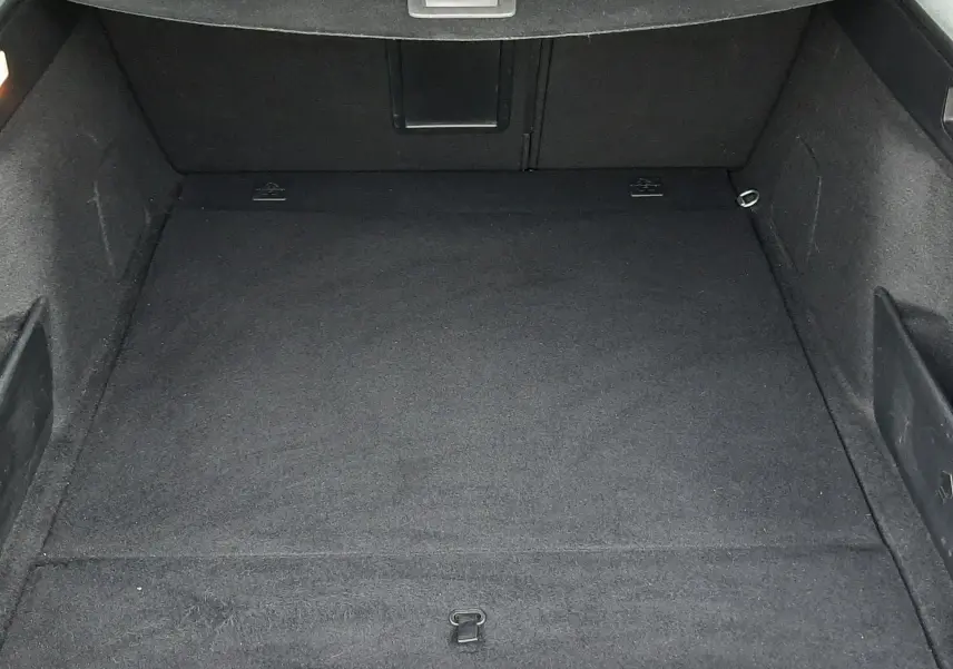 Vue plongeante sur le coffre spacieux et noir du Peugeot 308 SW 1.2 PureTech 2021, avec cache-bagages déployé.