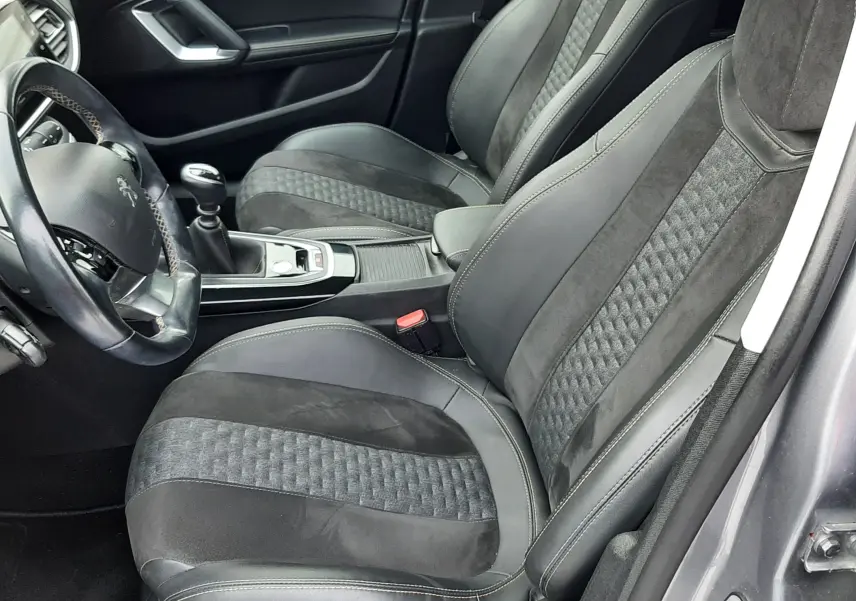 Vue intérieure côté conducteur de la Peugeot 308 SW 2021, sièges tissu et alcantara noirs avec volant cuir.