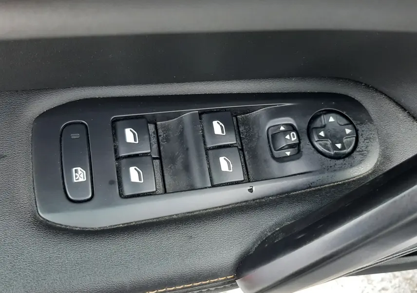 Gros plan sur les commandes de lève-vitres et réglage des rétroviseurs côté conducteur d'une Peugeot 308 SW gris Artense.