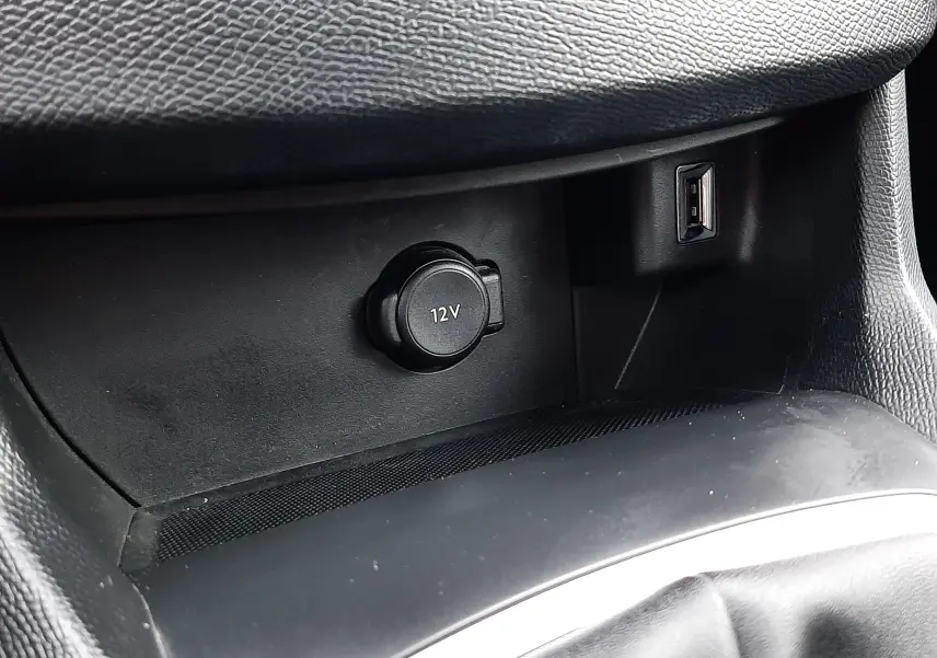 Gros plan intérieur sur la prise 12V et port USB dans la console centrale noire du Peugeot 308 SW gris Artense.