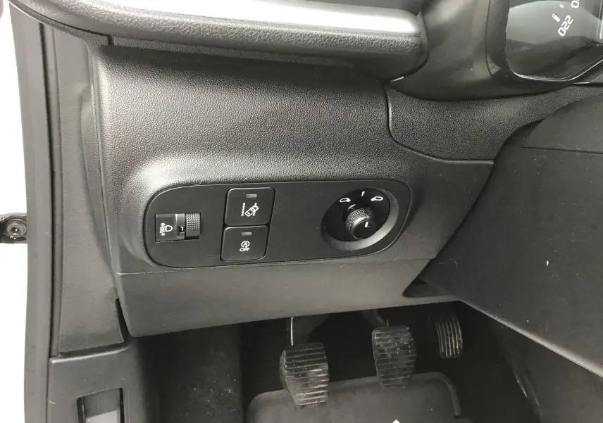 Vue intérieure côté gauche du tableau de bord d'une Citroën C3 Société blanche, montrant les commandes d'éclairage et les pédales.