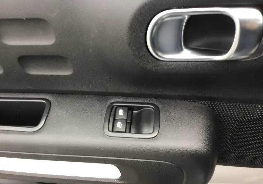 Détail de la porte côté gauche de la Citroën C3 Société blanche, avec commandes électriques des vitres et poignée argentée.
