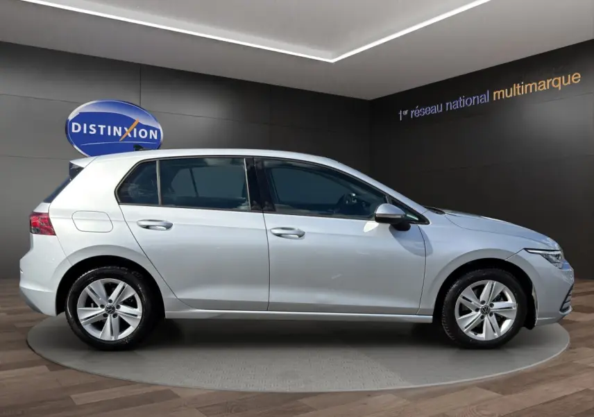 Volkswagen Golf gris clair vue de profil côté gauche dans un showroom avec jantes alliage cinq branches.