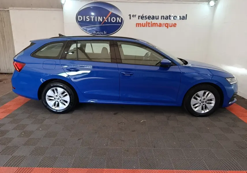 Vue de profil côté gauche d'une Skoda Octavia break bleue dans un showroom avec logo Distinxion en arrière-plan.