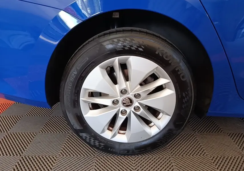 Gros plan sur la roue arrière droite d’une Skoda Octavia bleue avec jante alliage argentée et logo central distinctif.