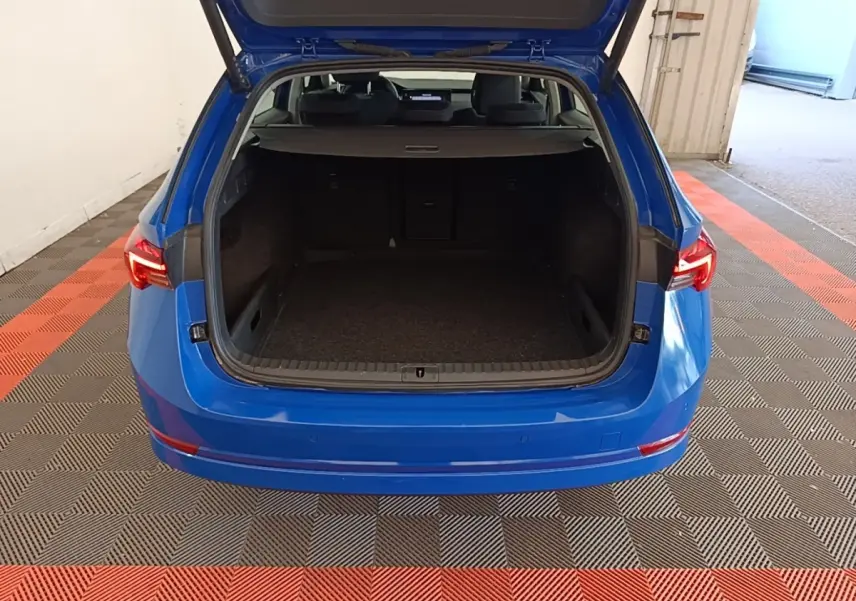 Vue arrière d’un Skoda Octavia bleu électrique 2024 avec coffre ouvert et intérieur spacieux visible.
