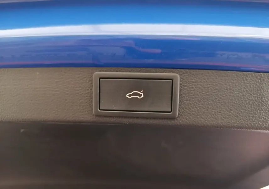 Bouton d'ouverture du coffre sur la bordure intérieure d'une Skoda Octavia 2024 bleu électrique.