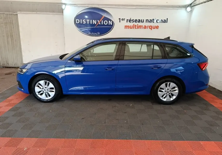 Vue de profil côté gauche d'une Skoda Octavia break 2024 bleu vif, avec jantes alliage et rails de toit noirs.