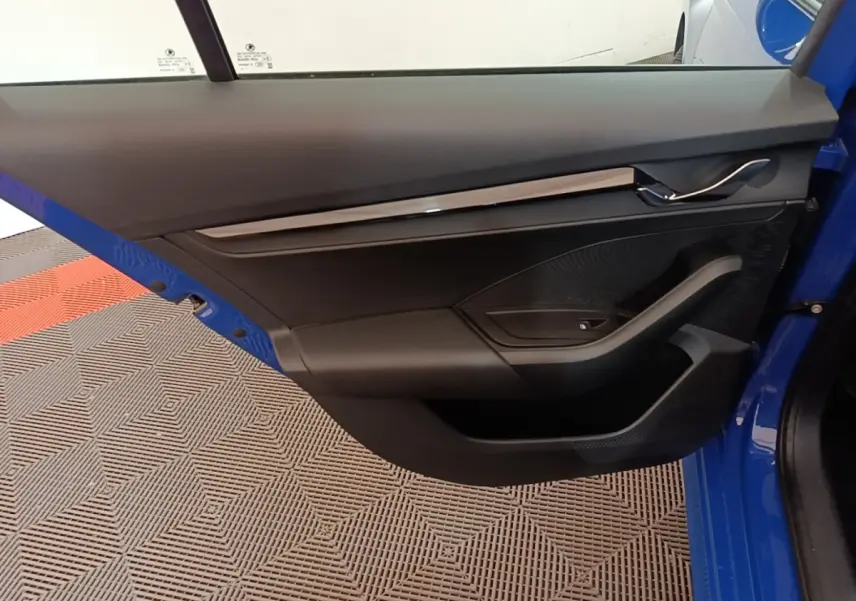 Vue intérieure de la porte avant gauche bleue d'une Skoda Octavia 2024 avec garniture noire et poignée chrome.