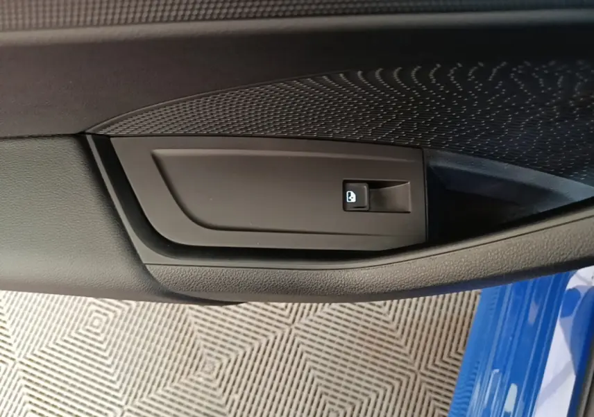 Détail de la poignée intérieure de porte côté conducteur d'une Skoda Octavia 2024 bleue avec bouton de verrouillage.