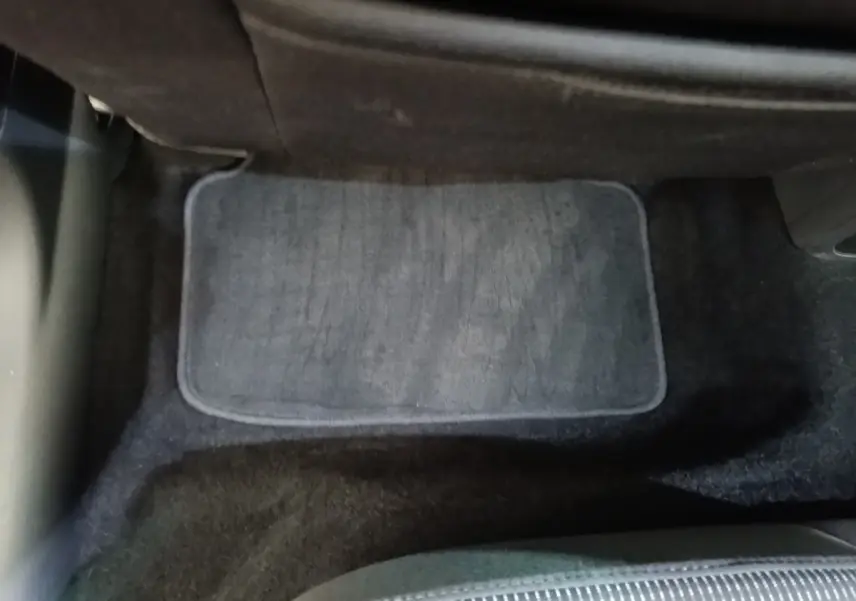 Vue intérieure du plancher arrière avec tapis de sol gris et siège tissu noir partiel d'une Skoda Octavia 2024.