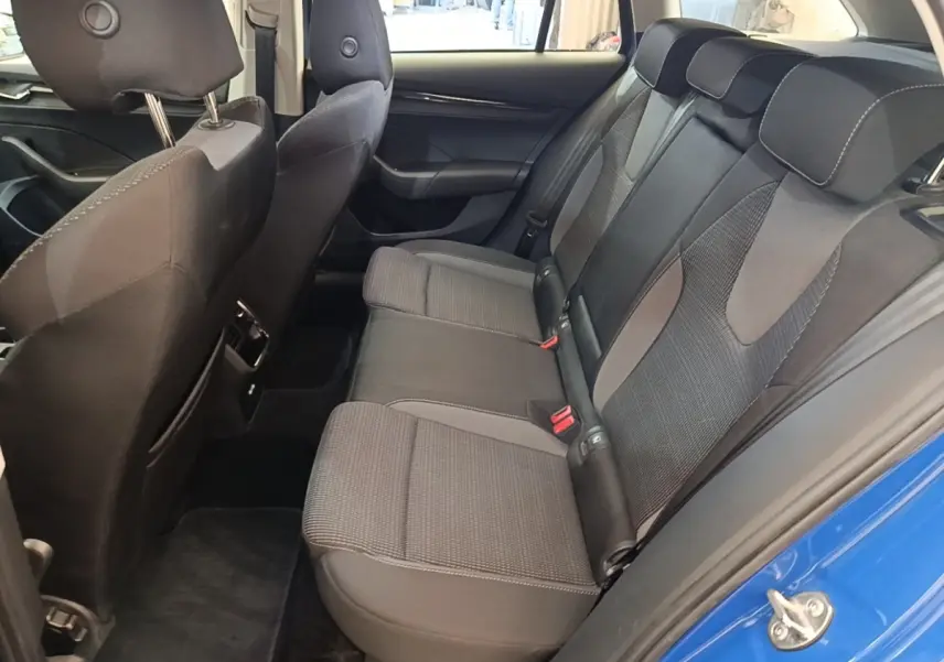Vue intérieure côté gauche montrant la banquette arrière grise et noire de la Skoda Octavia 2024 avec porte bleue ouverte.