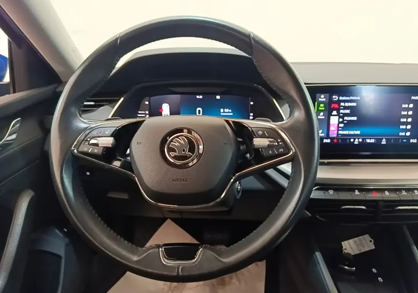 Vue intérieure centrée sur le volant cuir noir de la Skoda Octavia 2024 avec tableau de bord digital et écran tactile.