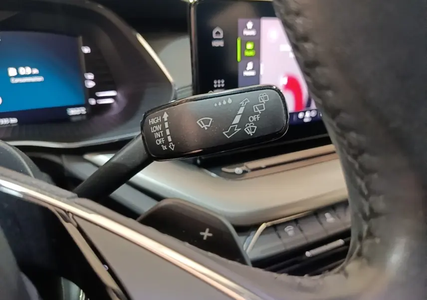 Gros plan sur la manette d’essuie-glace noire côté gauche du volant cuir dans l’habitacle de la Skoda Octavia 2024.