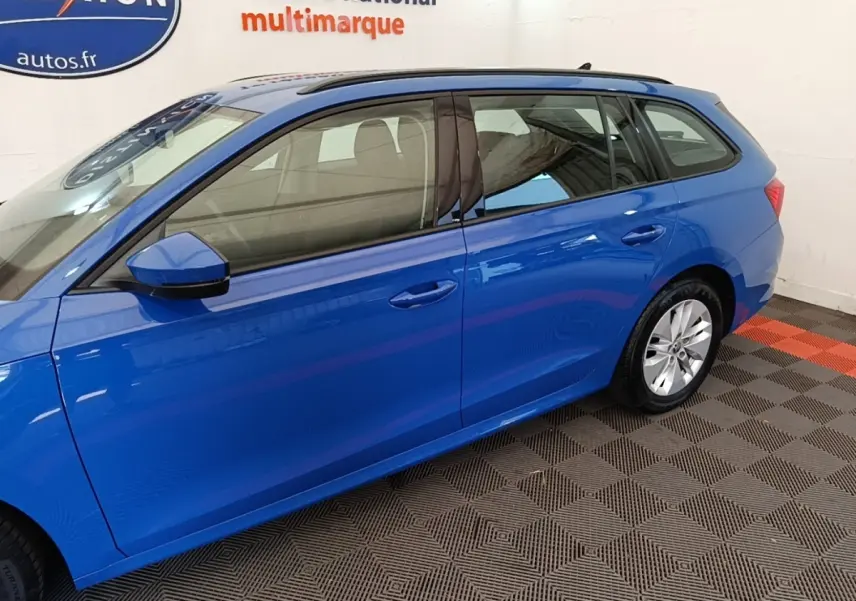 Vue latérale droite d'une Skoda Octavia break 2024 bleu vif avec rétroviseurs électriques et jantes alliage.