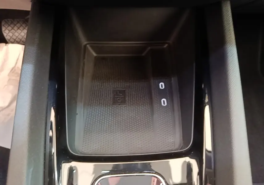 Vue rapprochée de la console centrale noire de la Skoda Octavia 2024, avec zone de recharge sans fil et ports USB visibles.