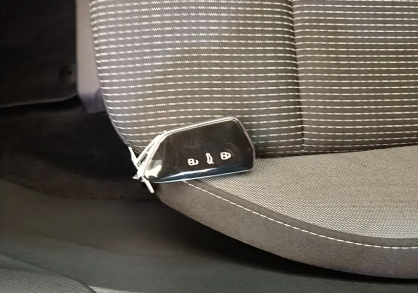 Clé de voiture noire posée sur le siège avant gris à motifs rayés de la Skoda Octavia 2024.