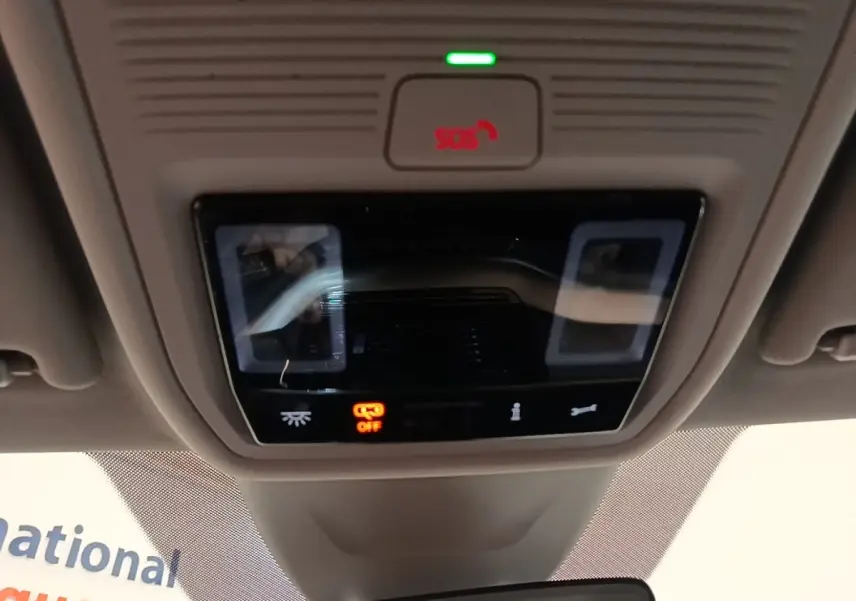 Gros plan sur le panneau de commande de toit intérieur gris avec bouton SOS rouge et éclairage tactile éteint.