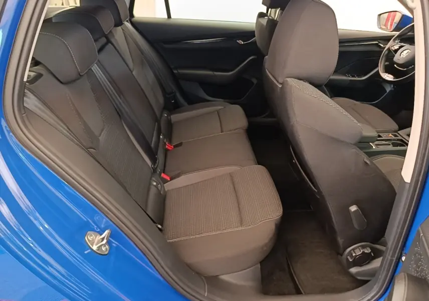 Vue intérieure côté gauche montrant la banquette arrière noire et la porte bleue ouverte d'une Skoda Octavia 2024.