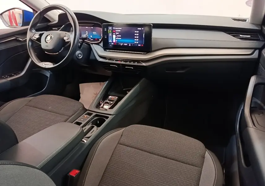 Vue intérieure côté conducteur de la Skoda Octavia 2024, tableau de bord noir avec écran tactile central et volant cuir.