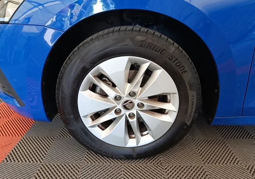 Gros plan sur la roue avant gauche d'une Skoda Octavia bleue, avec jante argentée et pneu Bridgestone.