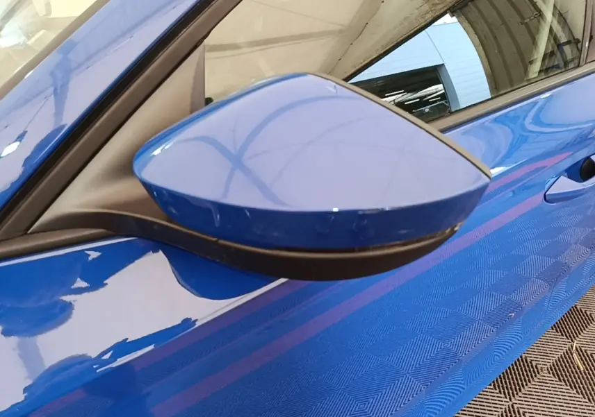 Gros plan sur le rétroviseur côté conducteur bleu d’une Skoda Octavia 2024, avec reflet de la carrosserie bleue.
