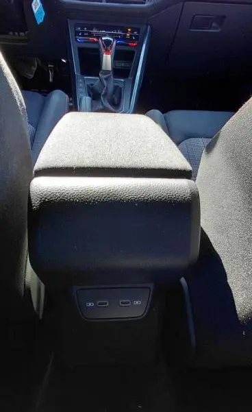 Vue intérieure centrée sur l'accoudoir central et la console de la Volkswagen Polo GTI noire 2024 avec commandes et ports USB visibles.