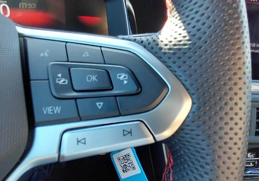 Gros plan sur le volant sport perforé côté gauche du Volkswagen Polo GTI noir avec commandes intégrées et écran digital.