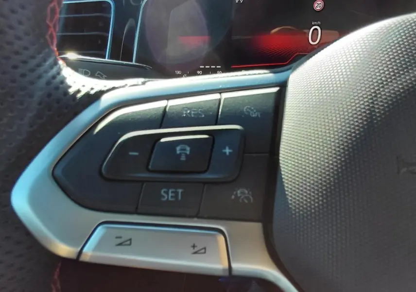Gros plan sur les commandes du volant sport de la Volkswagen Polo GTI 2024, avec finition noire et surpiqûres rouges.
