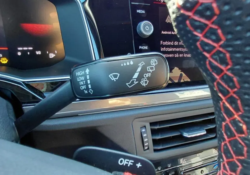 Gros plan sur la commande des essuie-glaces et volant sport avec surpiqûres rouges dans l’habitacle d’une Volkswagen Polo GTI 2024.