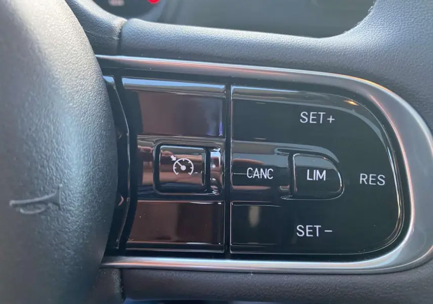 Gros plan sur les commandes du régulateur de vitesse sur le volant noir de la Fiat 500 électrique 2022.
