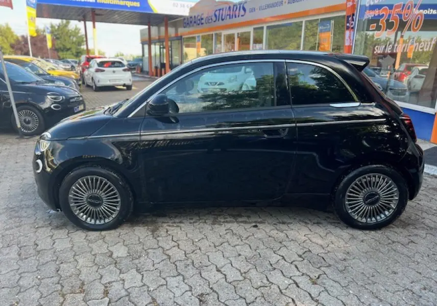 Profil côté gauche d'une FIAT 500 électrique noire 2022, avec jantes stylisées et poignées de porte discrètes.