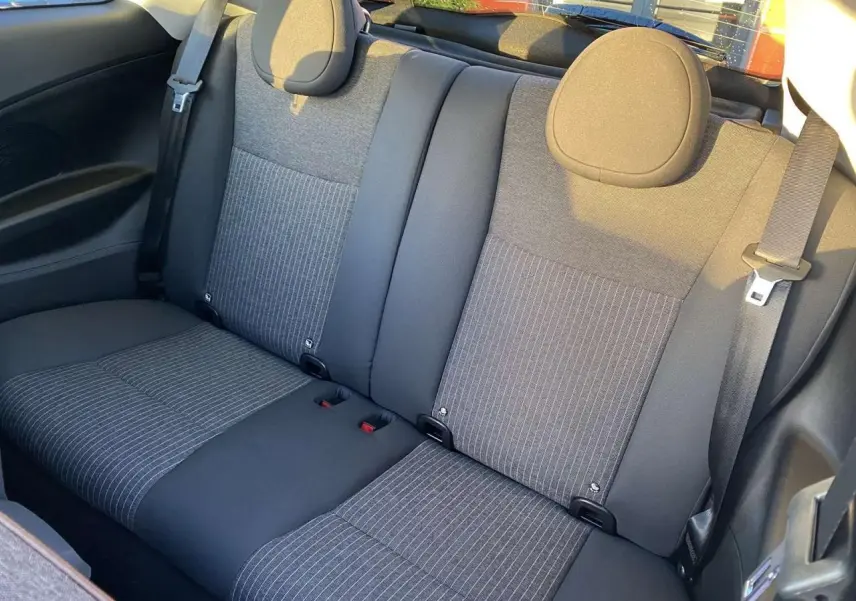Vue intérieure arrière des sièges arrière en tissu gris foncé à rayures verticales de la Fiat 500 électrique noire 2022.