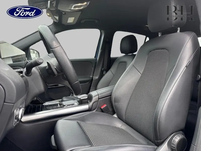 Vue intérieure côté conducteur du Mercedes GLA 250 e Business Line avec sièges en tissu/similicuir noir et volant cuir multifonction.
