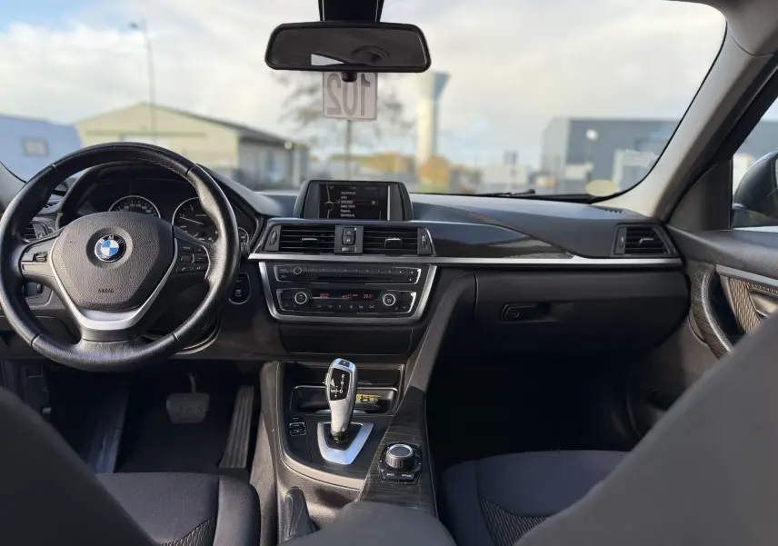 Intérieur de BMW Série 3 320D 2013 vu de face, tableau de bord noir avec console centrale et volant multifonction.