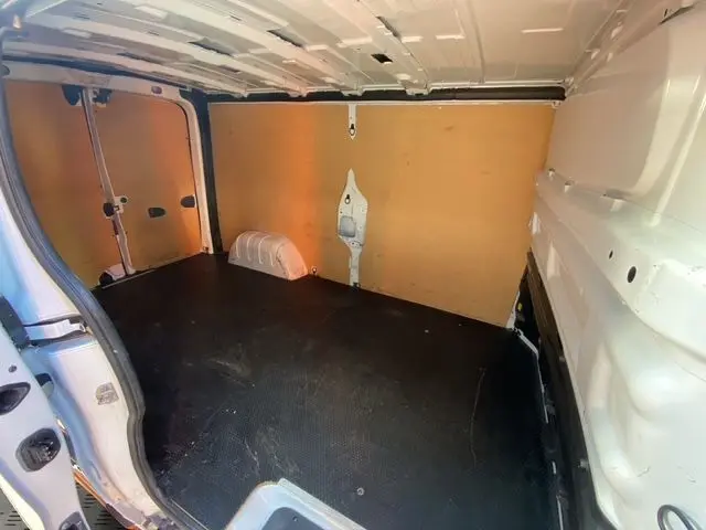 Vue intérieure du coffre arrière du Renault Trafic Fourgon blanc 2023, montrant l'aménagement bois et le plancher noir.