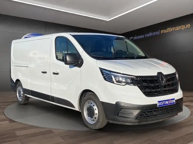 Vue 3/4 avant d’un Renault Trafic Fourgon blanc 2023 avec kit bois, présenté en intérieur sur plateforme rotative.