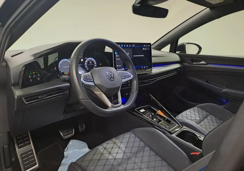 Intérieur côté conducteur de la Volkswagen Golf 2.0 TDI 150 DSG7 R Line 2024 avec éclairage bleu et sièges tissu à motif.